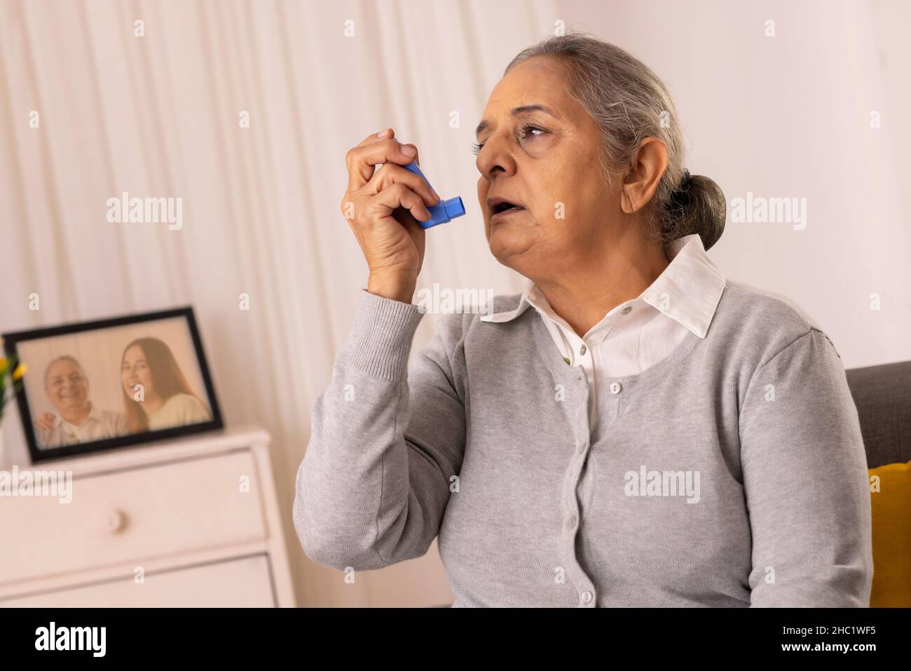 Frau im hohen Alter, die ihren Asthma-Inhalator zu Hause verwendet Stockfoto