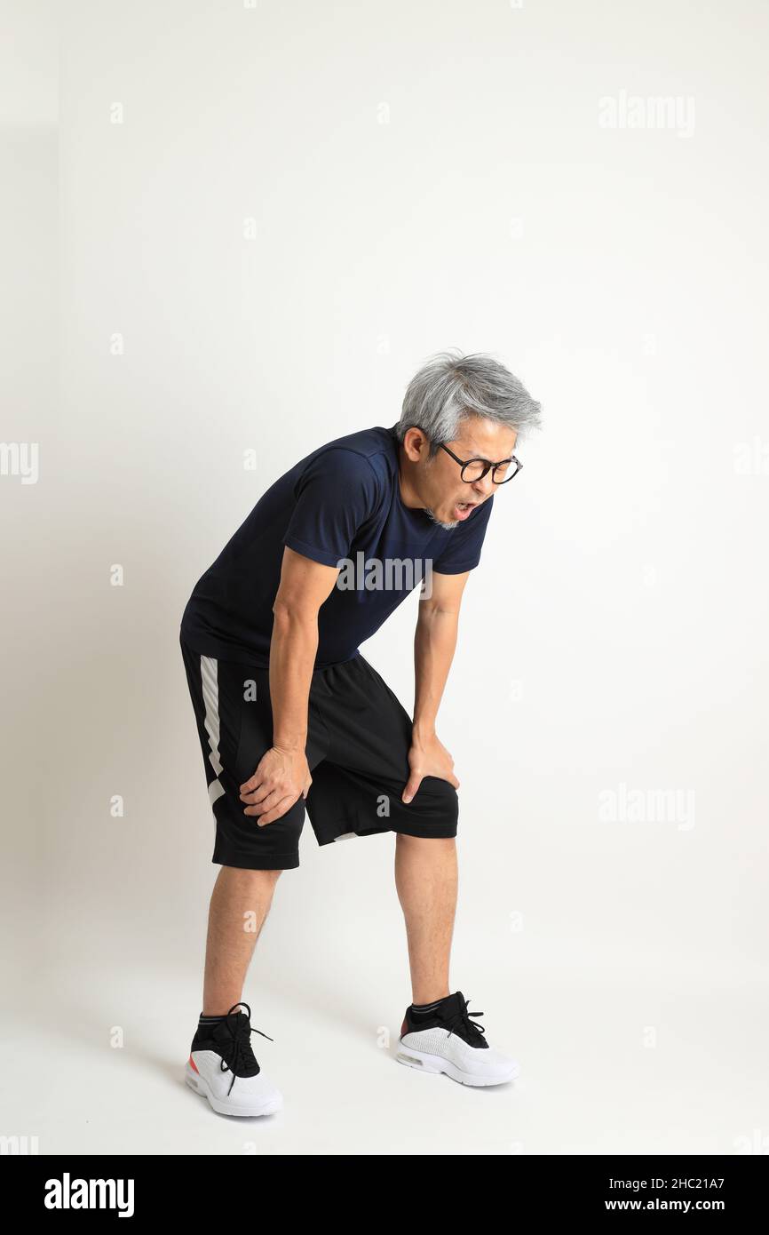 Der asiatische Senioren mit Sportkleidung auf weißem Hintergrund. Stockfoto