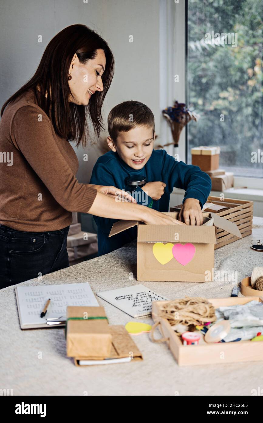 Charity Care Box, Spendenbox, Geschenkpaket Ideen. Glückliche Familie, Mutter, Kind und Hund, die Mitarbeiter in die Spendenbox stecken. Care Package Delivery, Winter Stockfoto