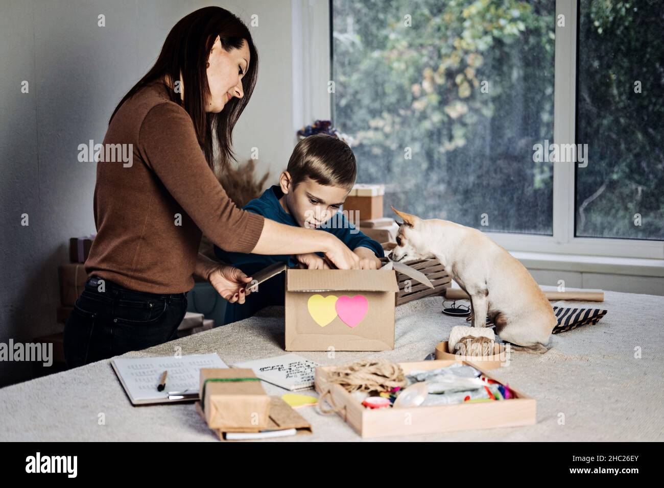 Charity Care Box, Spendenbox, Geschenkpaket Ideen. Glückliche Familie, Mutter, Kind und Hund, die Mitarbeiter in die Spendenbox stecken. Care Package Delivery, Winter Stockfoto