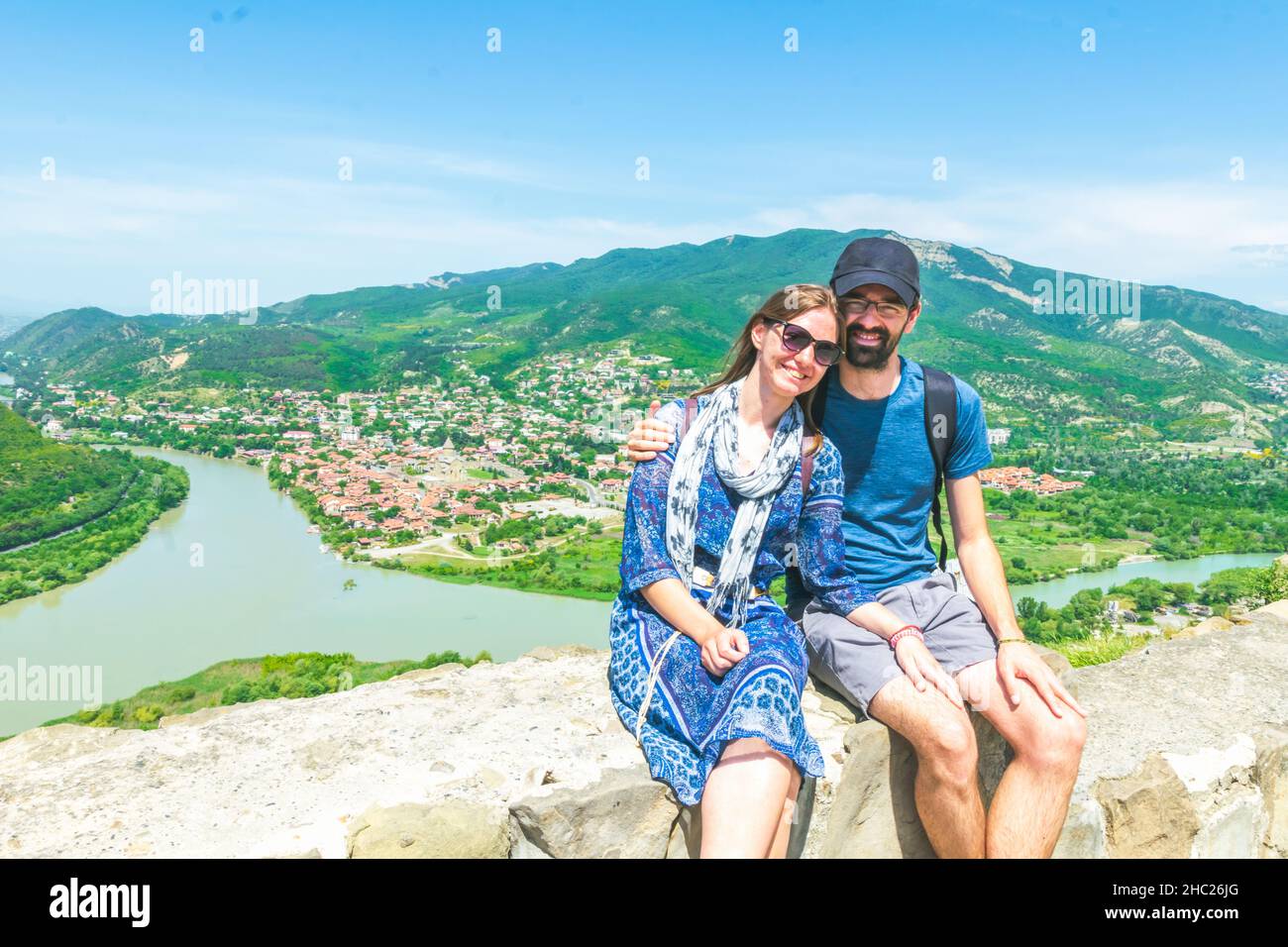 Das Paar sitzt zusammen mit dem malerischen Panorama-Berg und Mzcheta-Blick im Hintergrund und posiert für ein Reisefoto. Reisen im Sommer und Tourismus in Ca Stockfoto