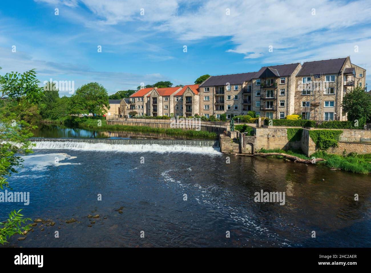 Sommerblick auf den Fluss Wharfe Wehr und Ferienwohnungen am Fluss in Wetherby, West Yorkshire Stockfoto