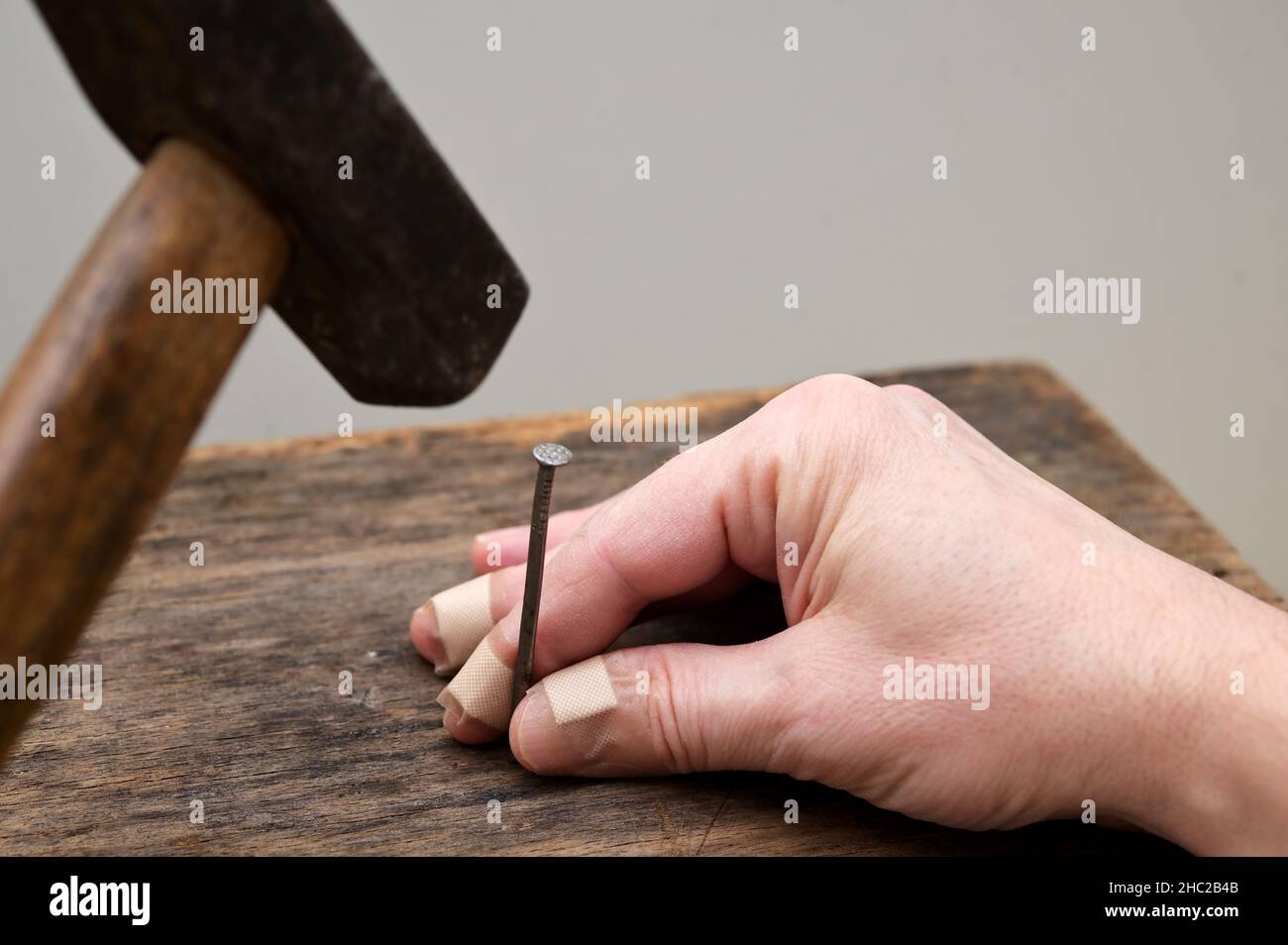 Motivationskonzept. Menschenunfall verletzt seinen Finger mit Einem Holzhammer Stockfoto