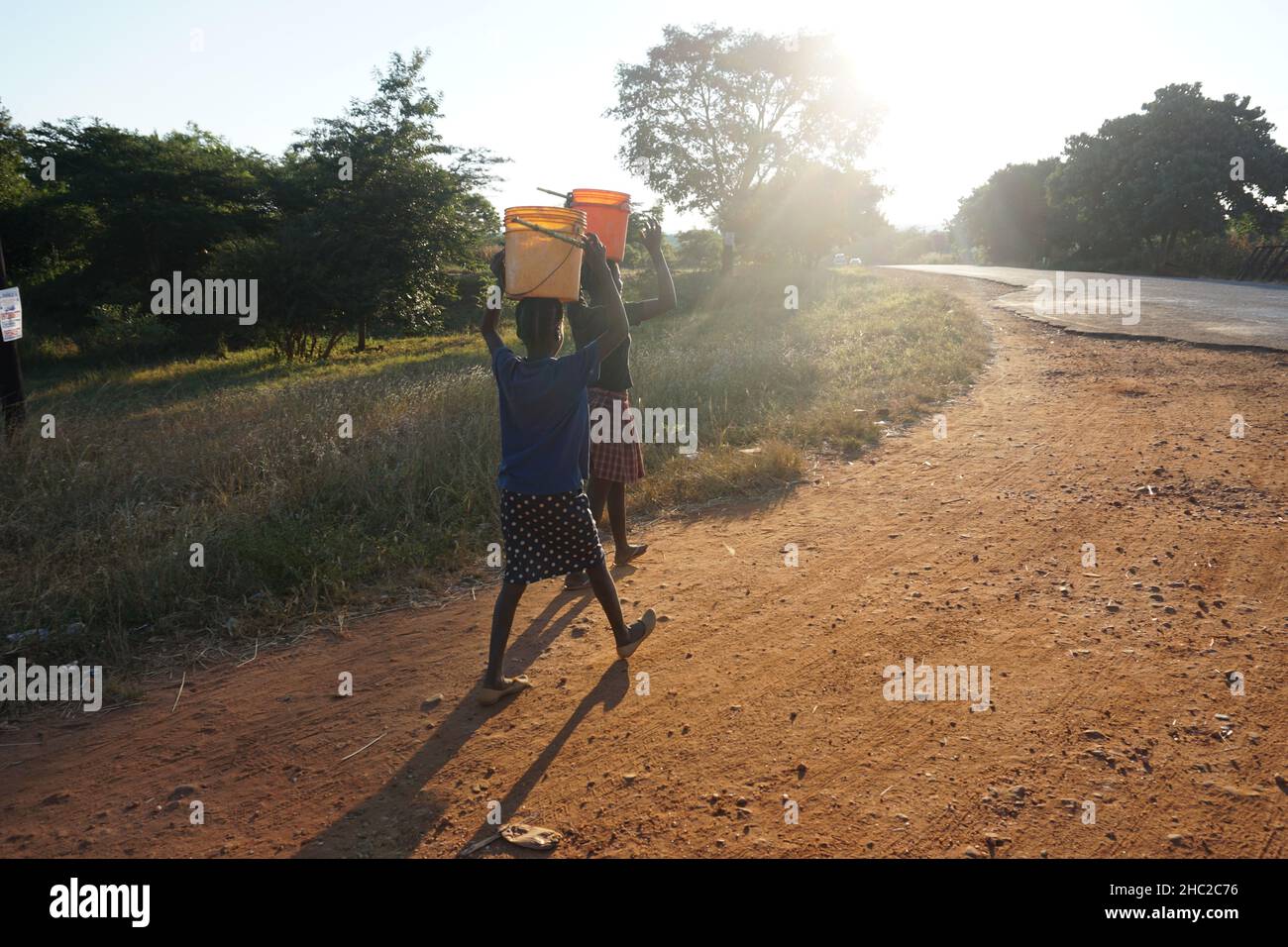 (211217) -- LUSAKA, 17. Dezember 2021 (Xinhua) -- zwei Mädchen tragen Eimer Wasser im Bezirk Rusunsa der Provinz Lusaka, Sambia, 5. April 2021. DAZU „Feature: Verbesserter Zugang zu Wasser im ländlichen Sambia hilft Mädchen, in der Schule besser zu arbeiten“ (Foto: Lillian Banda/Xinhua) Stockfoto