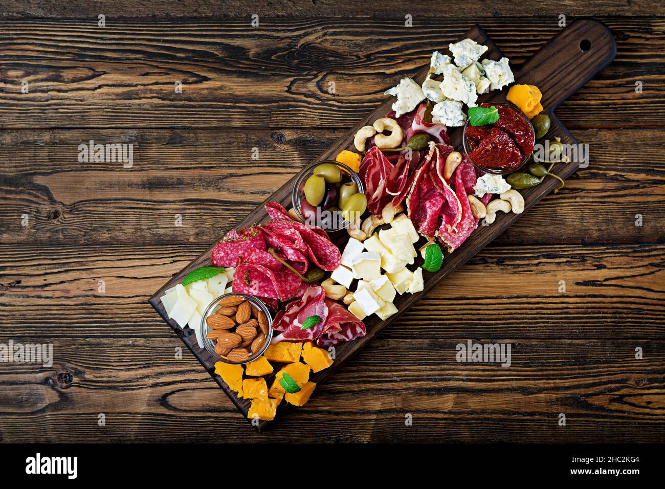 Antipasti-Platte mit Speck, Dörrfleisch, Wurst, Blauschimmelkäse und Trauben auf einem hölzernen Hintergrund catering. Ansicht von oben Stockfoto