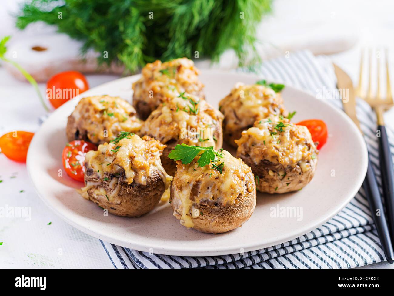 Gebackene Pilze gefüllt mit Hühnerfleisch, Käse und Kräutern auf Leuchtplatte. Stockfoto