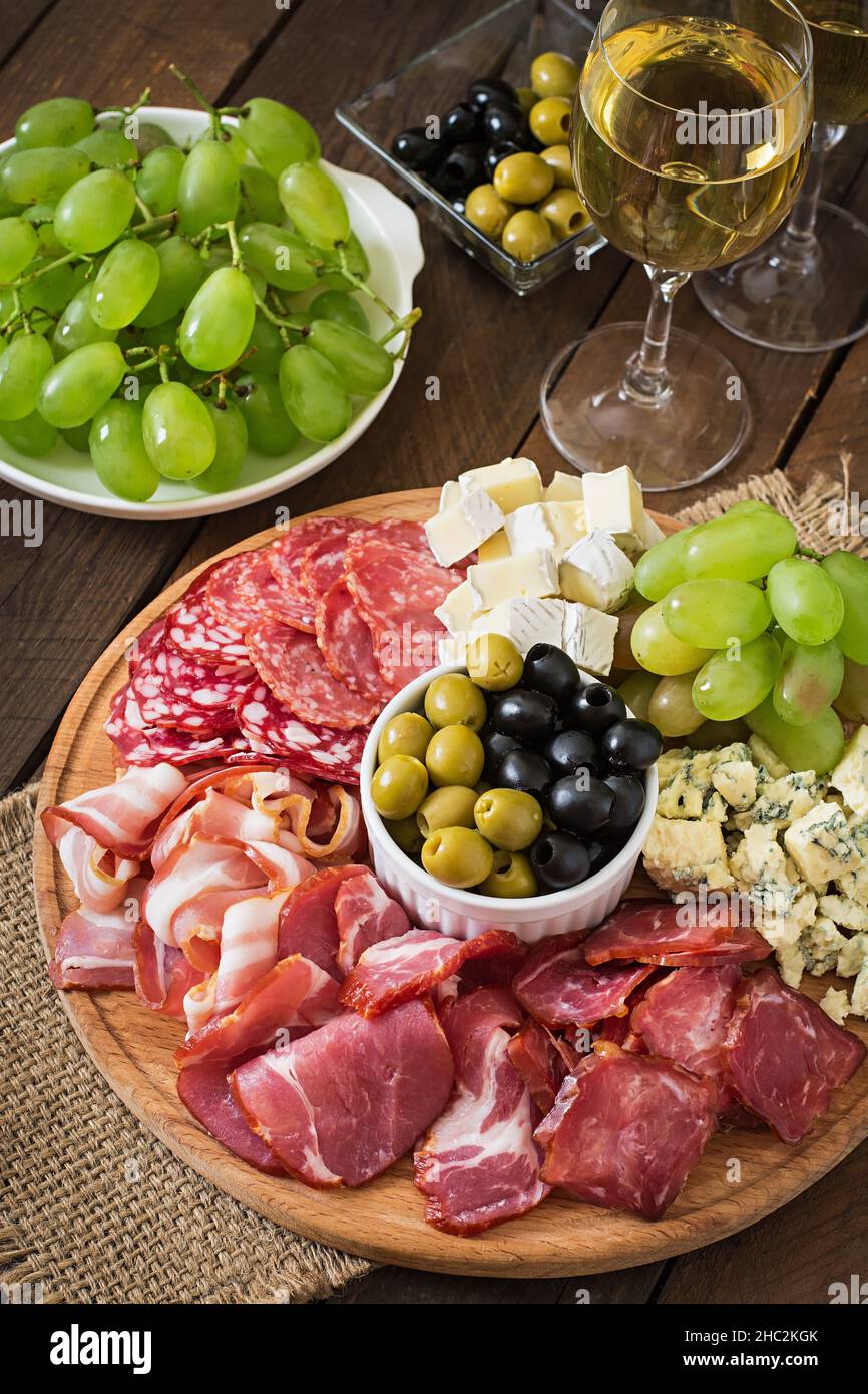 Antipasti Teller mit Speck, Trockenfleisch, Salami, Käse und Trauben auf einem hölzernen Hintergrund catering Stockfoto