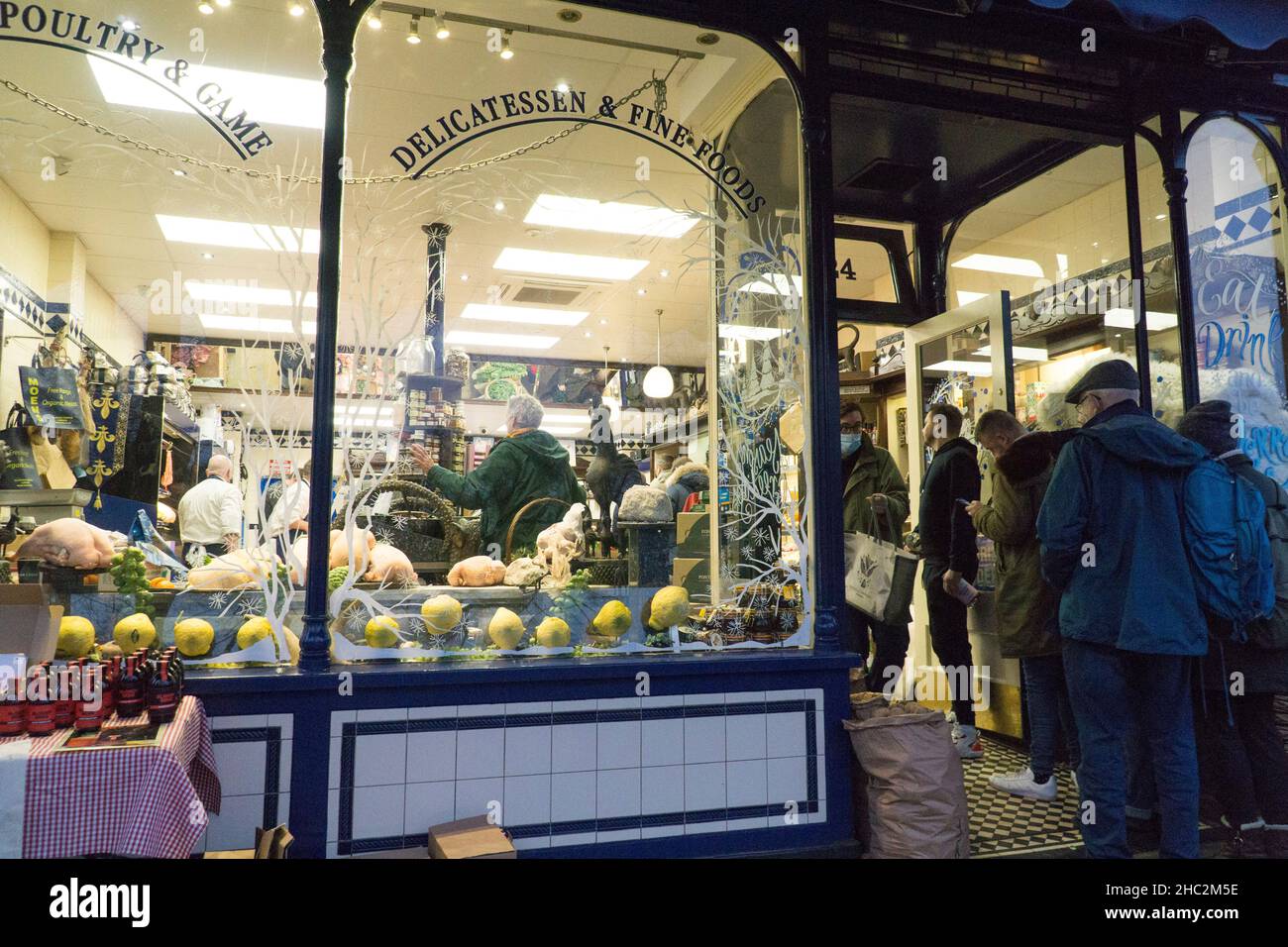 London, Großbritannien, 23. Dezember 2021: Kunden stehen vor der lokalen Metzgerei Moen and Sons in der Altstadt von Clapham. Kunden, die Truthähne, Gänse oder Enten zu Weihnachten sammeln, standen auf einer Seite in der Schlange. Diejenigen, die Fleisch, Käse und Delikatessen kaufen wollten, standen auf der anderen Seite in der Schlange. Anna Watson/Alamy Live News Stockfoto