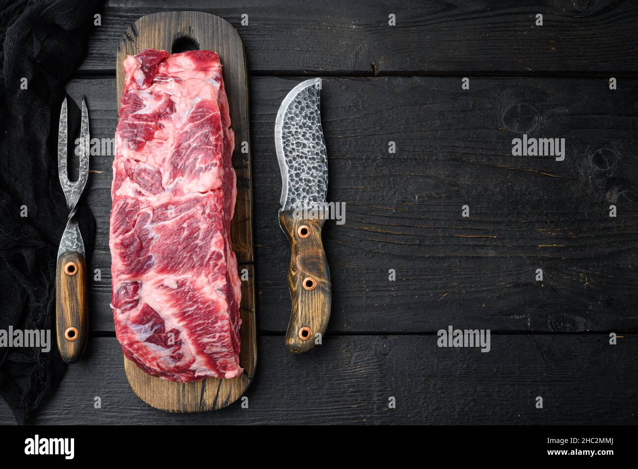 RAW Rib Eye Beef Steak Marmorfleisch im ganzen Schnitt, auf schwarzem Holztisch Hintergrund, Draufsicht flach liegend, mit Platz für Text Stockfoto