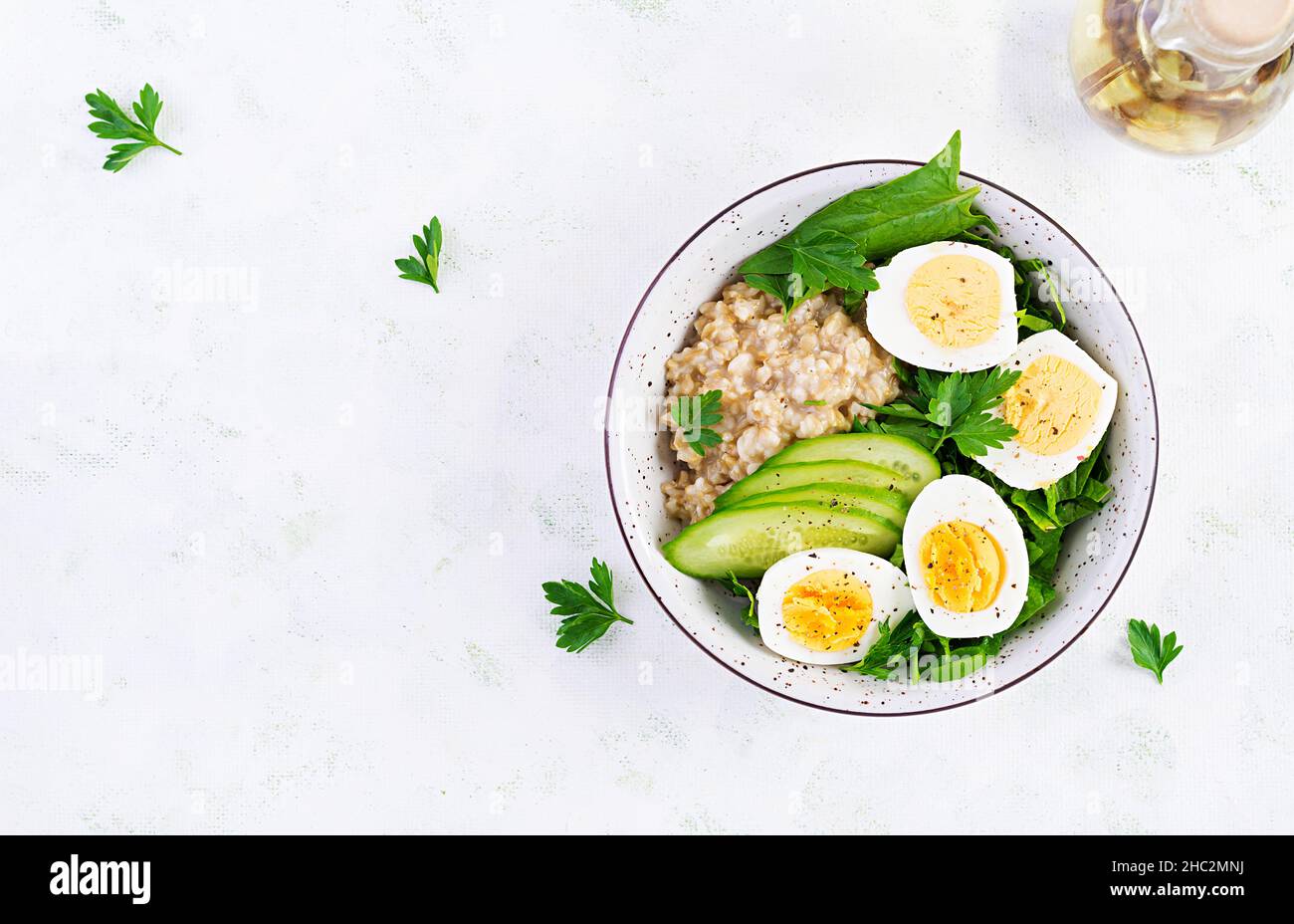 Frühstück Haferbrei mit gekochten Eiern, Gurken und grünen Kräutern. Gesunde, ausgewogene Ernährung. Draufsicht, oben Stockfoto