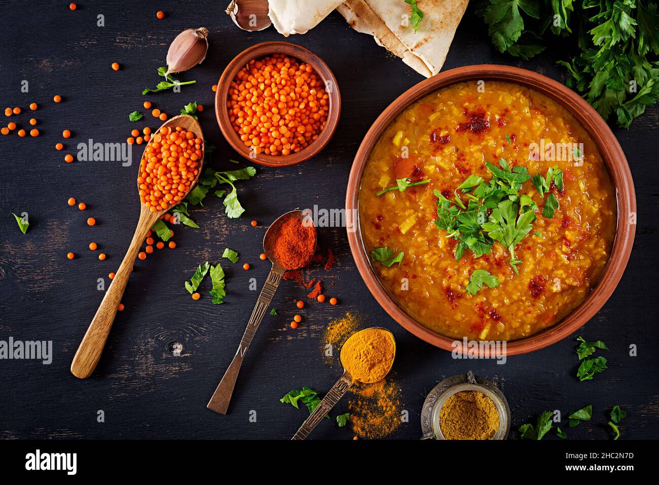 Indisches Dal. Essen. Traditionelle indische Suppe Linsen. Indische Dhal spicy Curry in der Schüssel, Gewürze, Kräuter, rustikale schwarz Holz- Hintergrund. Ansicht von oben. Authenti Stockfoto