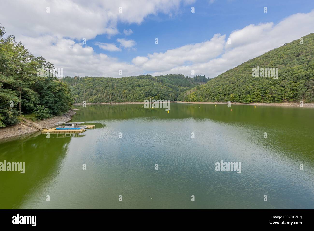 Landschaft des Staudamms Esch-sur-Sure, umgeben von üppigen grünen Bäumen im Tal mit grünen Hügeln im Hintergrund, sonniger Tag mit blu Stockfoto