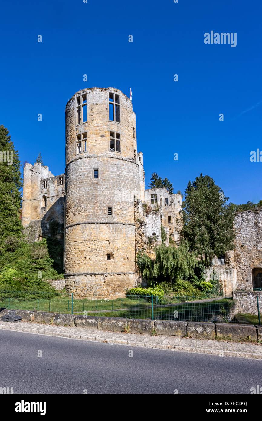 Landstraße und der verfallene Rundturm in den Ruinen der Burg Beaufort, Steinmauern, umgeben von üppigen Bäumen, sonnigen Sommertag mit einem Stockfoto