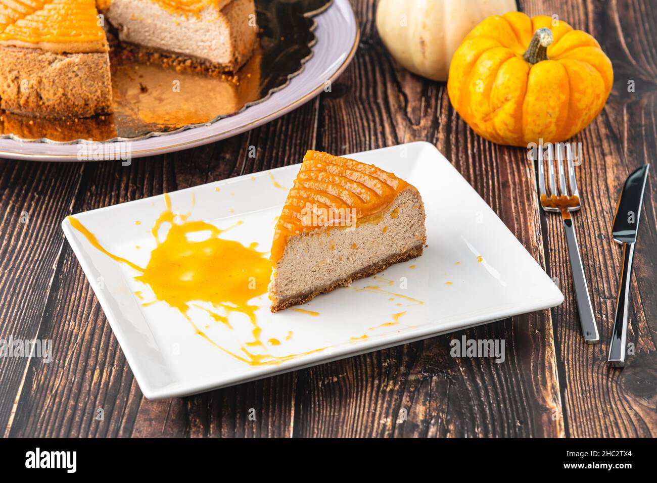 Köstlicher Kürbis-Käsekuchen in weißem Teller auf Holztisch Stockfoto