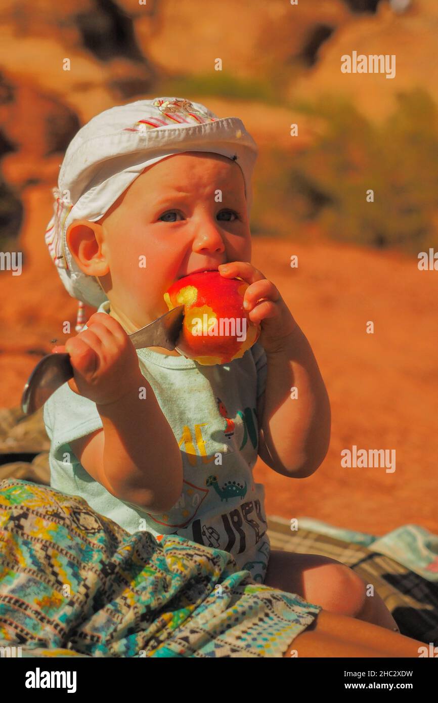 Ein süßes Kleinkind versucht bei einem Picknick einen Apfel zu essen. Stockfoto