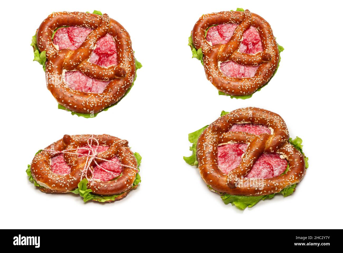Brezel mit Salami und Salat isoliert auf weißem Hintergrund. Leckerer Snack. Stockfoto