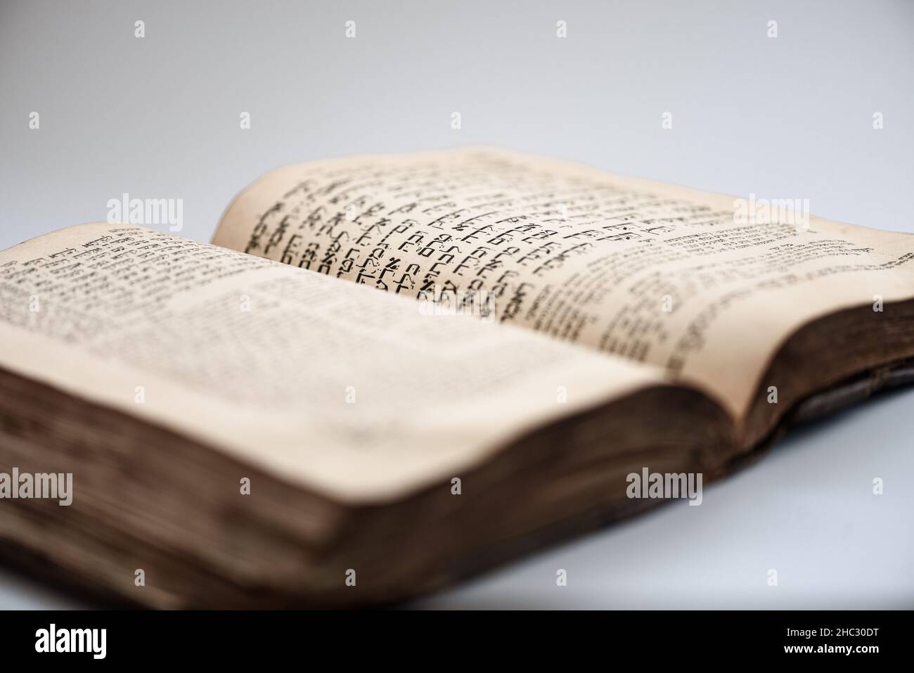 Abgenutztes schäbiges jüdisches Buch. Offene Seite des Buches Genesis mit verschwommenem hebräischen Text. Nahaufnahme. Selektiver Fokus Stockfoto