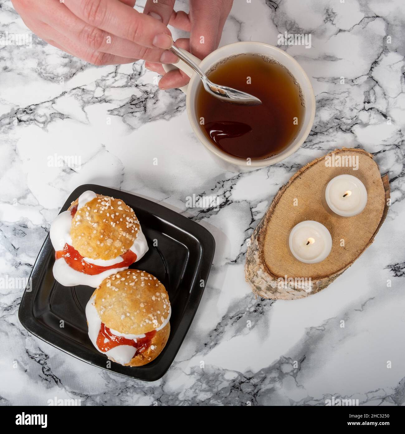 Helsinki / Finnland - 12. DEZEMBER 2021: Aufnahme einer Platte mit traditionellen shrove-Brötchen und einer Teetasse auf einer Granitplatte Stockfoto