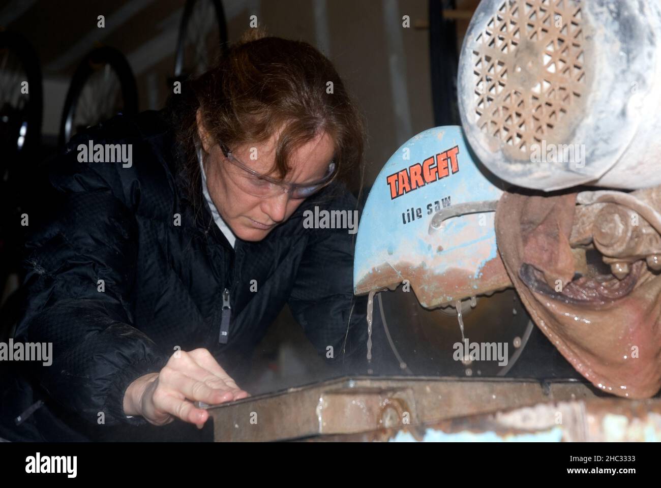 Eine Frau schneidet Fliese auf nasser Säge. Oregon Stockfoto