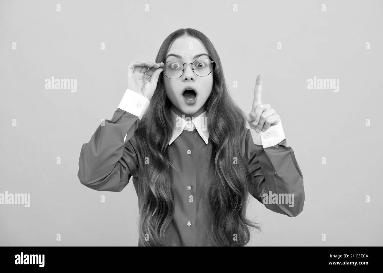 Schockiert Teenager-Mädchen in Brillen bekam geniale Idee halten erhobenen Finger gelben Hintergrund, clever Stockfoto