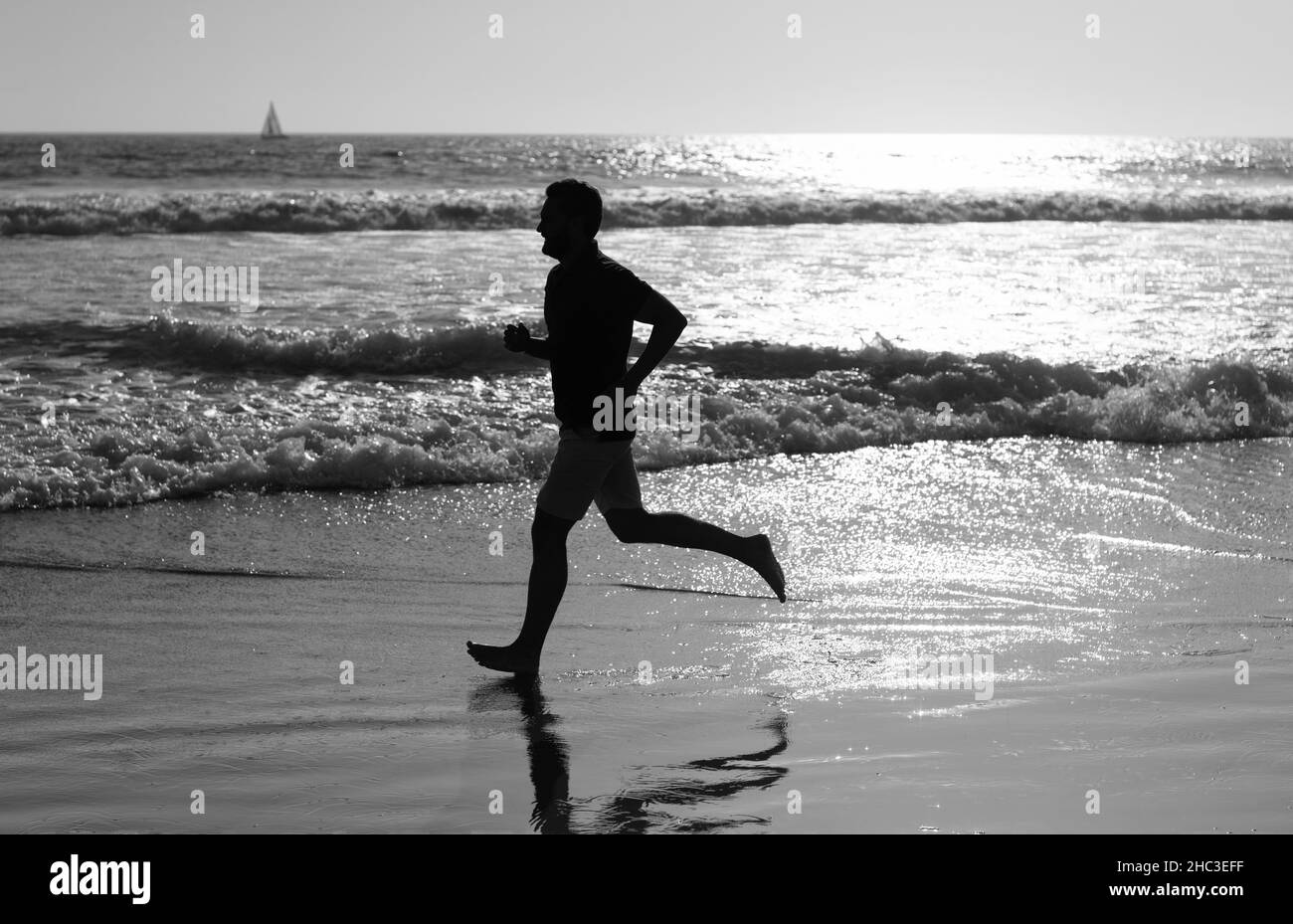 Sportler laufen schnell, um im Meer zu gewinnen. Morgendliche Workout-Aktivität. Gesunder Mann läuft am Strand. Stockfoto