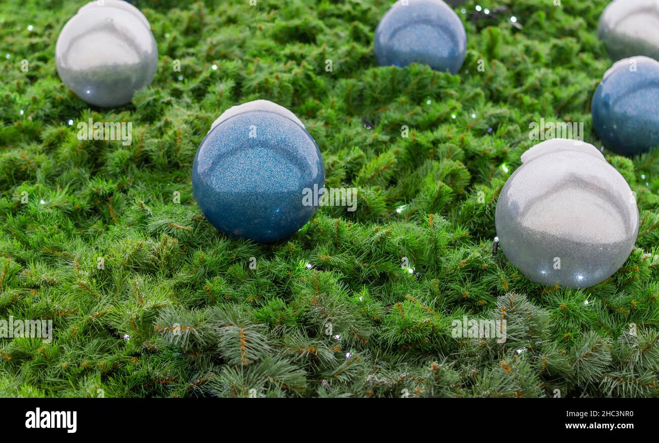 Grüne Nadeln, Kugeln aus glühenden Glühbirnen Girlanden. Textur aus einem Teil des Weihnachtsbaums. Stockfoto