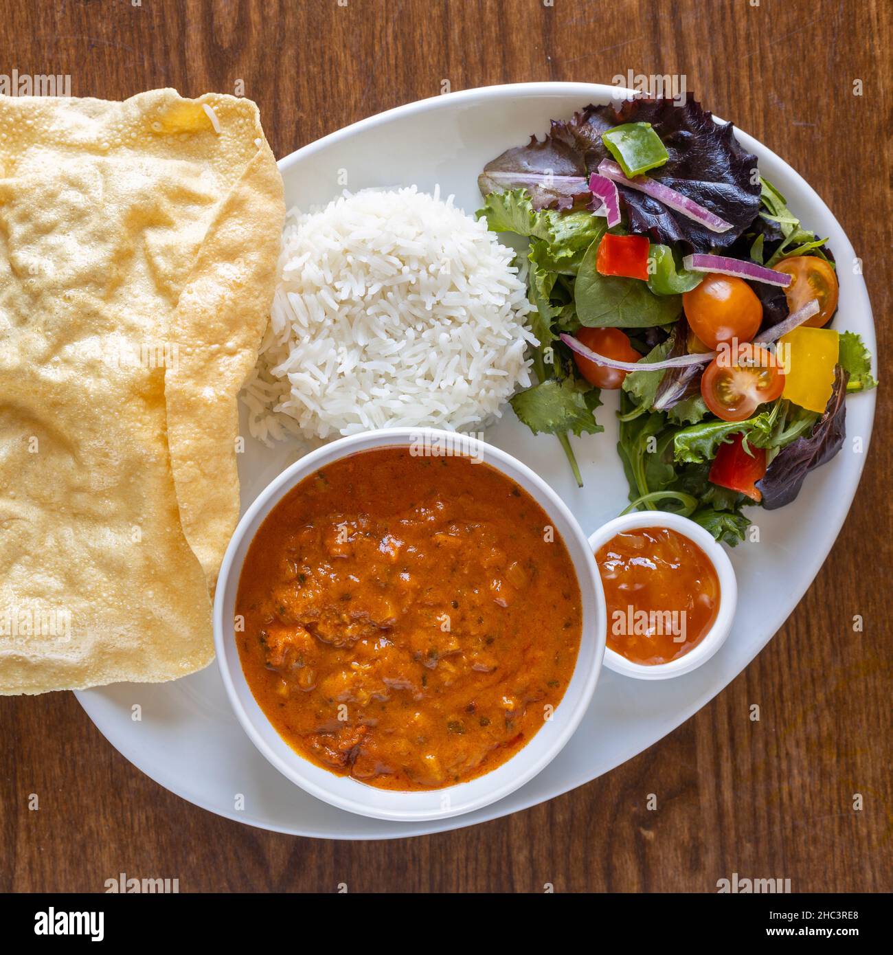 Blick von oben auf traditionelles indisches Essen. Die würzige Suppe, Salat, Reis und rote Sauce mit Brot Stockfoto