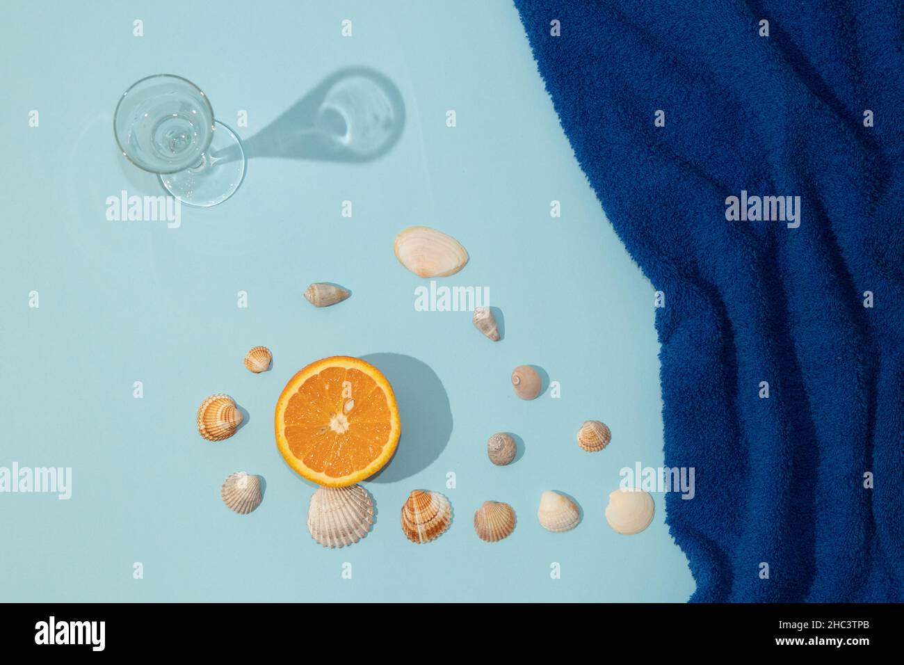 Sommerszene mit dunkelblauem Strandtuch und Glas und orangefarbenem Obst und Schale. Minimale Ästhetik. Stockfoto