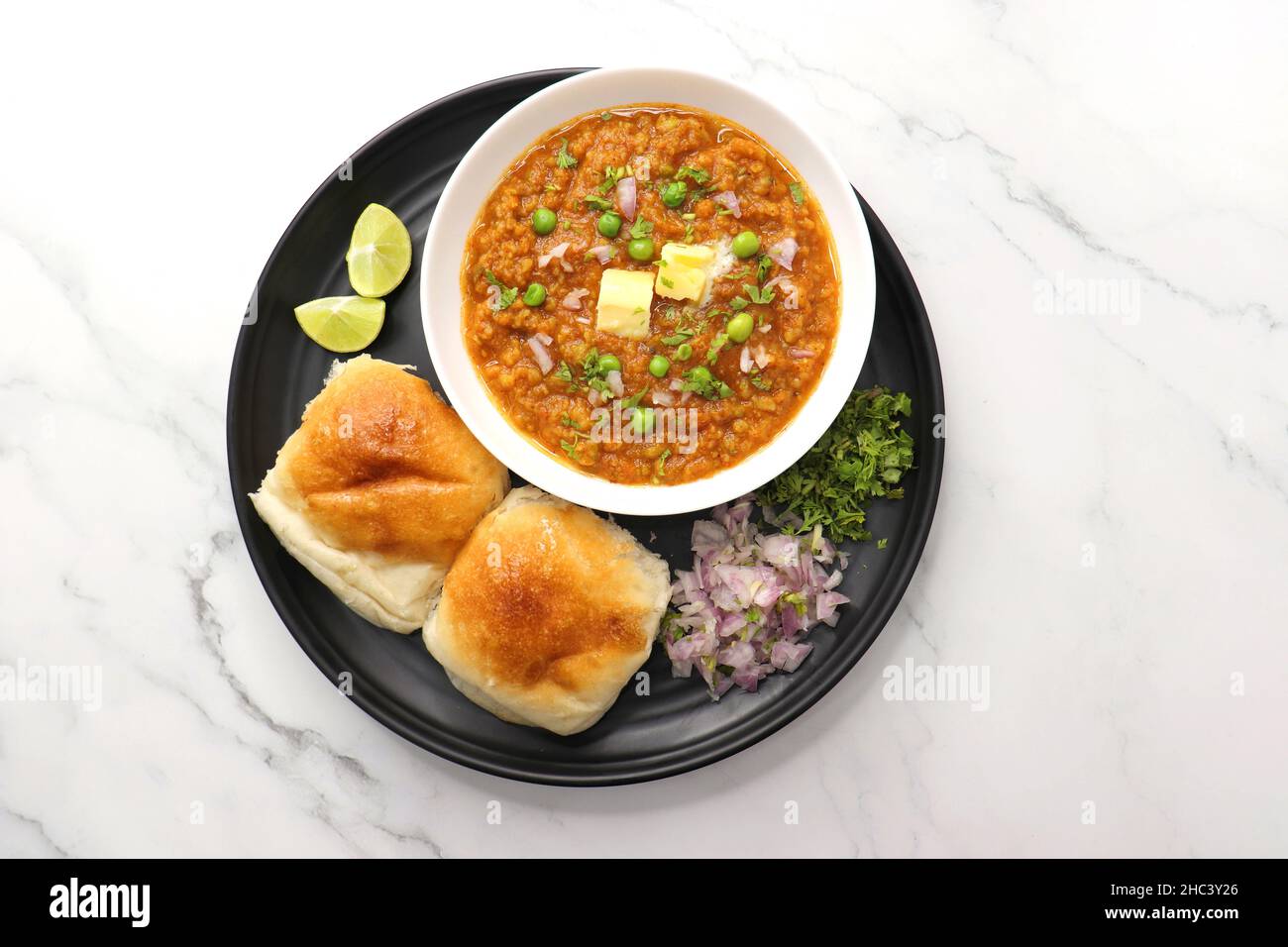 Pav Bhaji im indischen Stil der Mumbai Street, garniert mit Erbsen, rohen Zwiebeln, Koriander und Butter. Mit pav gebratene. Stockfoto