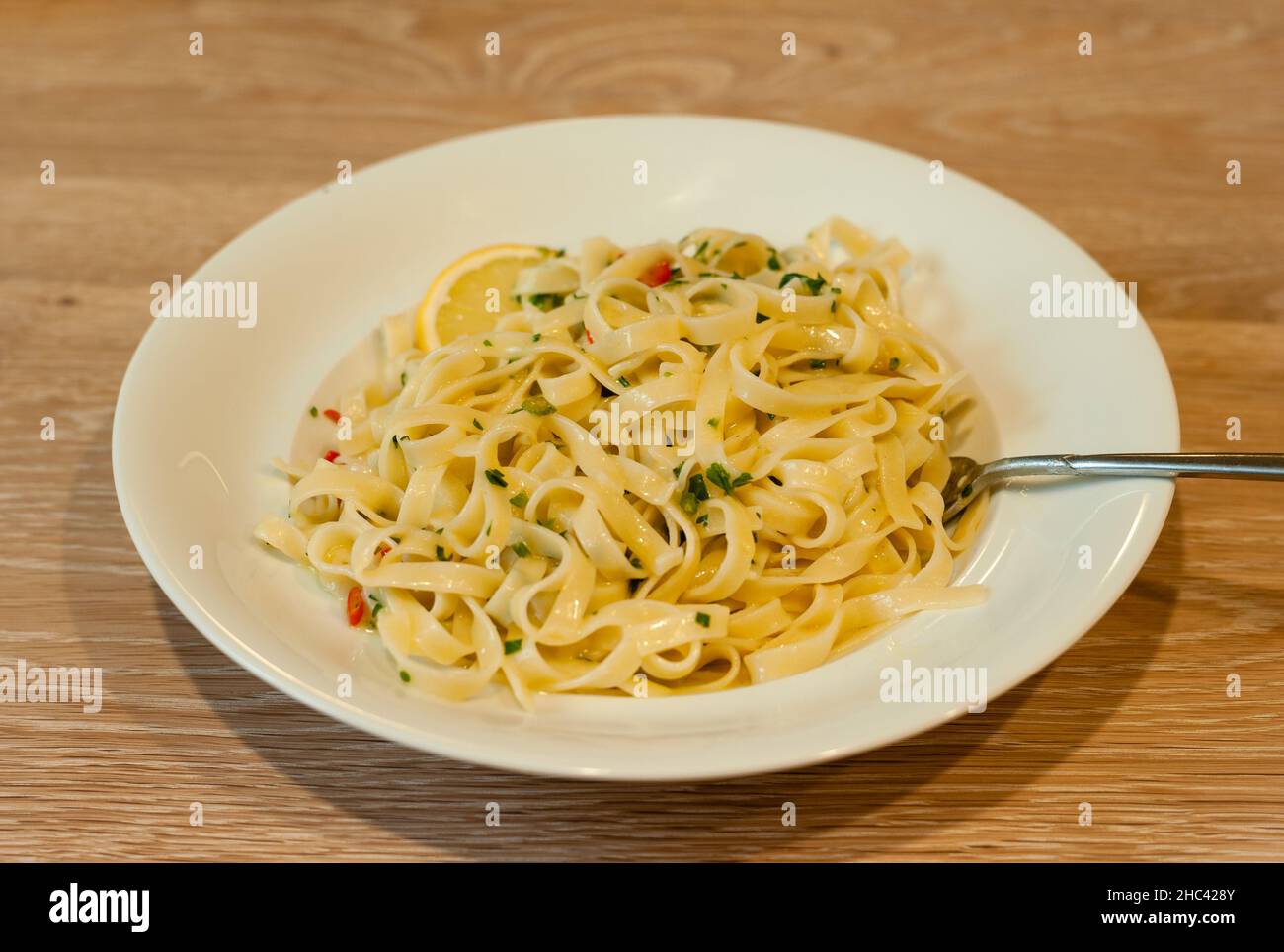 Italienische Zitronenpasta oder Tagliatelle al Limone auf einem weißen Teller mit Petersilie Stockfoto