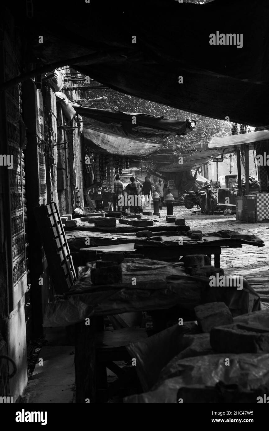 Monochromes Bild eines Straßenmarktes mit geschlossenen Geschäften auf der linken Seite Menschen, die auf der Straße gehen. Stockfoto