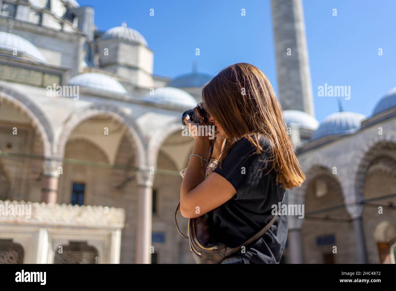 Braunhaarige Touristenfrau, die an einem sonnigen Tag in İstanbul die Suleymaniye-Moschee fotografiert. Reisen und aktiver Lifestyle, Sommerurlaubskonzept. Stockfoto