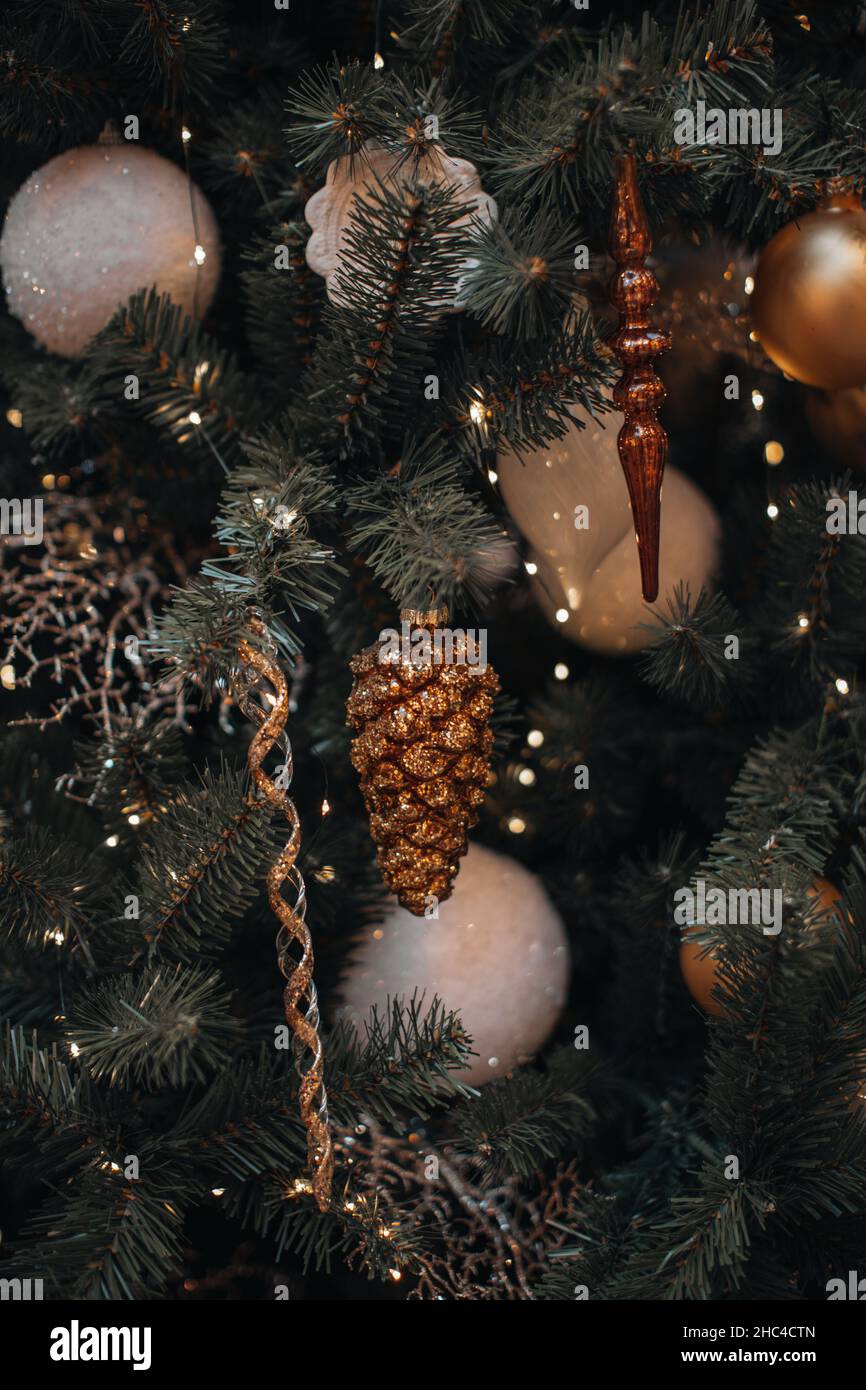 Goldener glitzernder Kegel und festliche Ornamente hängen am Weihnachtsbaum. Komposition zum neuen Jahr. Festliche Stimmung. Konzept für Winterurlaub Stockfoto