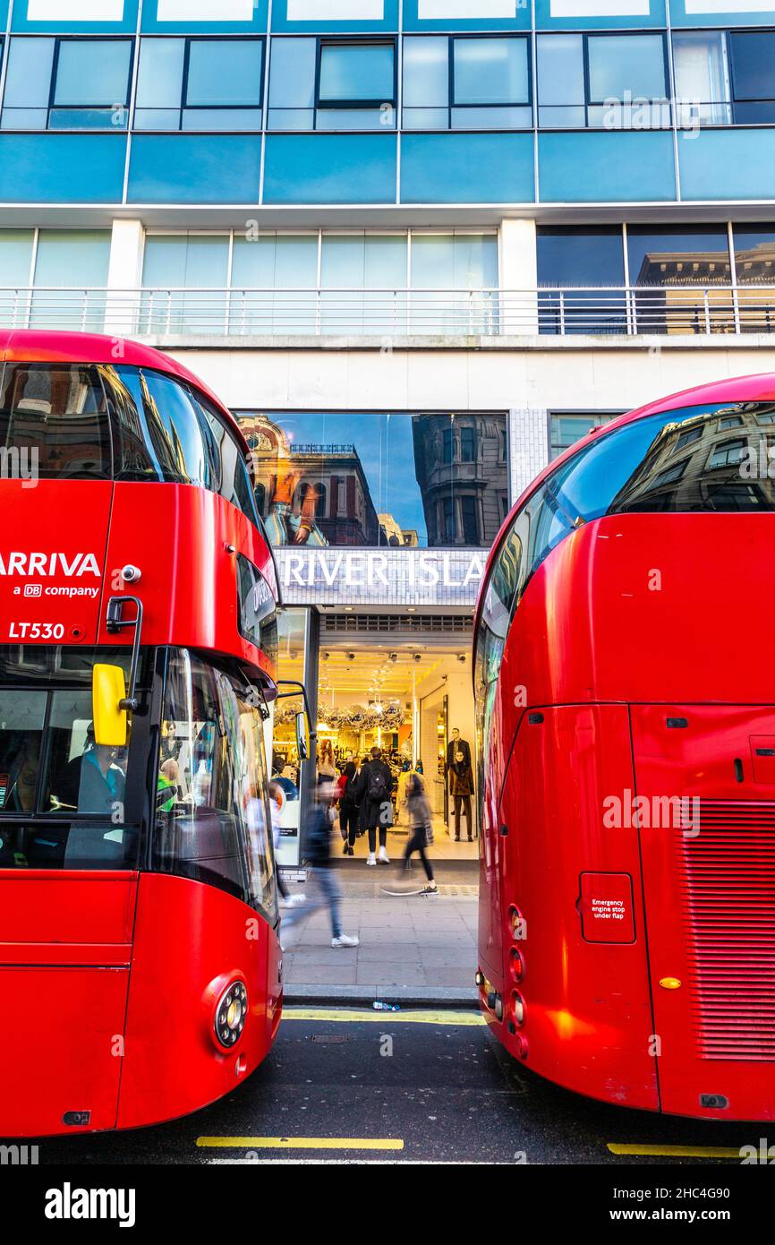 Fassade des River Island-Bekleidungsladens zwischen zwei roten Doppeldeckerbussen in der Oxford Street, London, Großbritannien Stockfoto