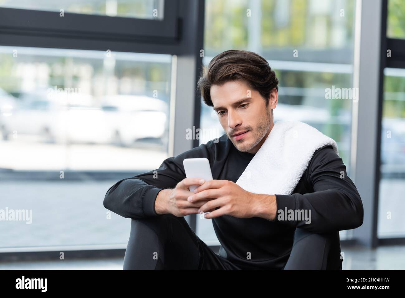 Brunette Sportler mit Handtuch mit Handy im Sportzentrum Stockfoto