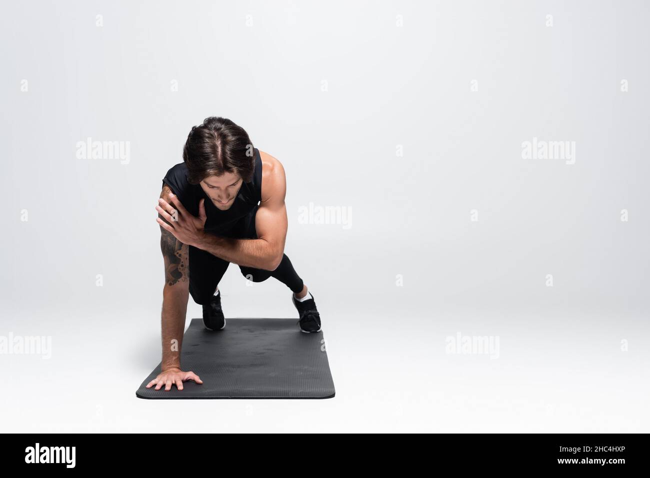 Ein sportlicher Sportler, der eine Planke auf grauem Hintergrund macht Stockfoto