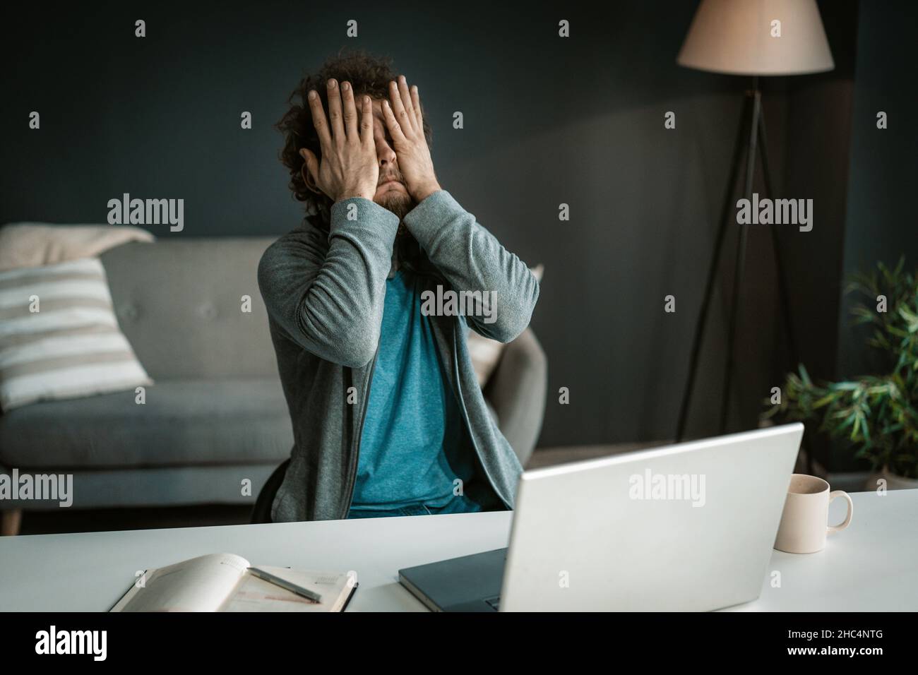 Online Business Owner hat Augen Ache nach einem harten Arbeitstag mit einem Computer. Der Mann bedeckt seine Augen mit den Händen, nachdem er lange auf den Laptop-Bildschirm geschaut hat. Nahaufnahme. Hochwertige Fotos Stockfoto