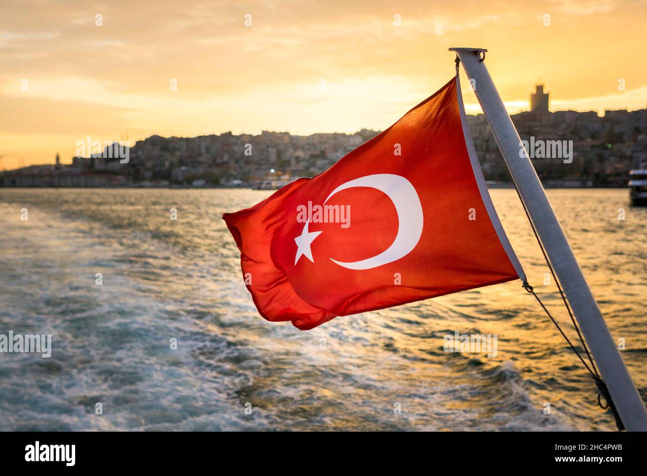 Die türkische Flagge flattert im Wind gegen Istanbul Bosporus bei Sonnenuntergang. Die Flagge der Republik Türkei. Stockfoto