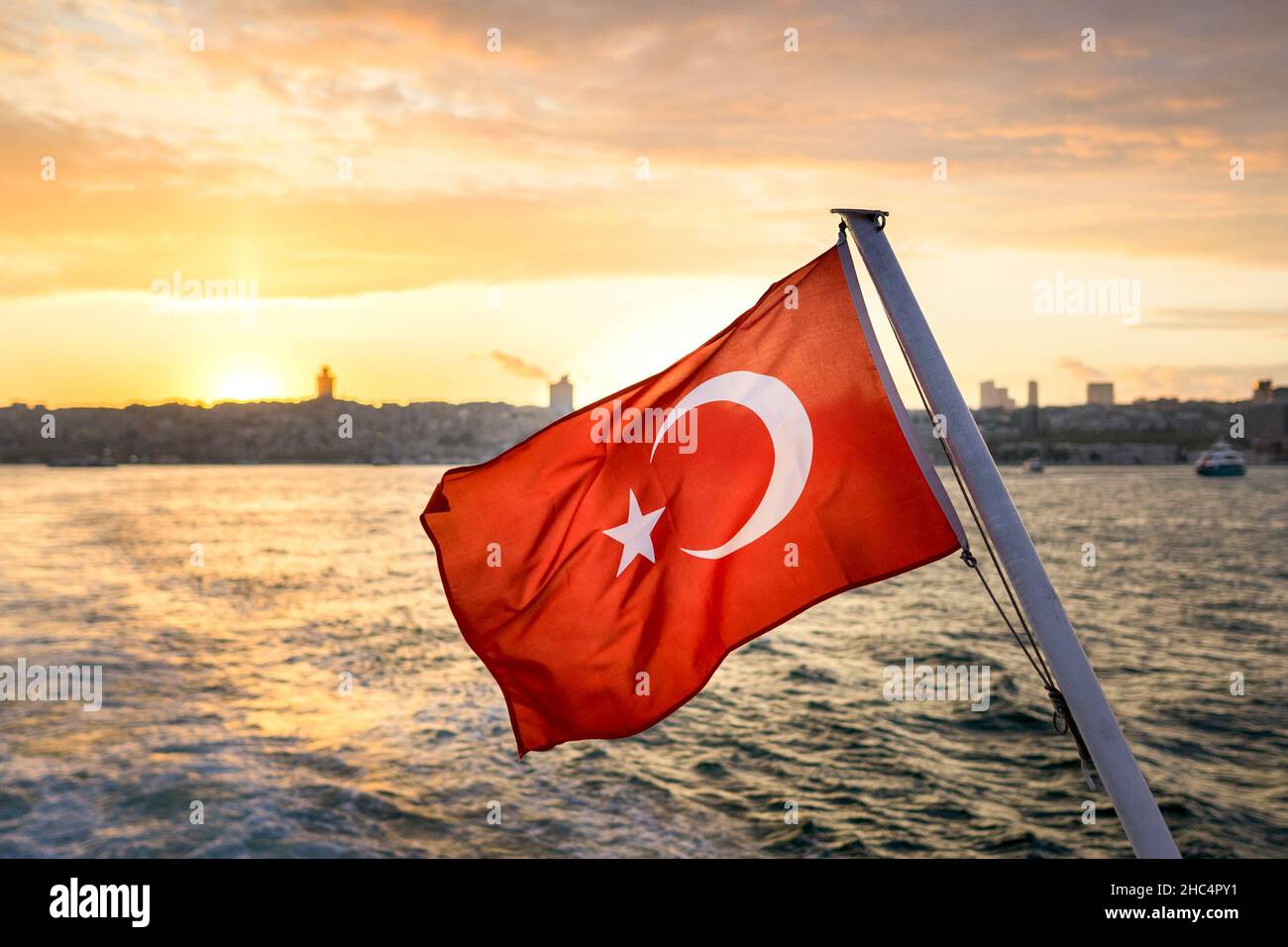 Bei Sonnenuntergang winkt die türkische Flagge im Wind gegen den Istanbuler Bosporus. Die Flagge der Republik Türkei. Stockfoto