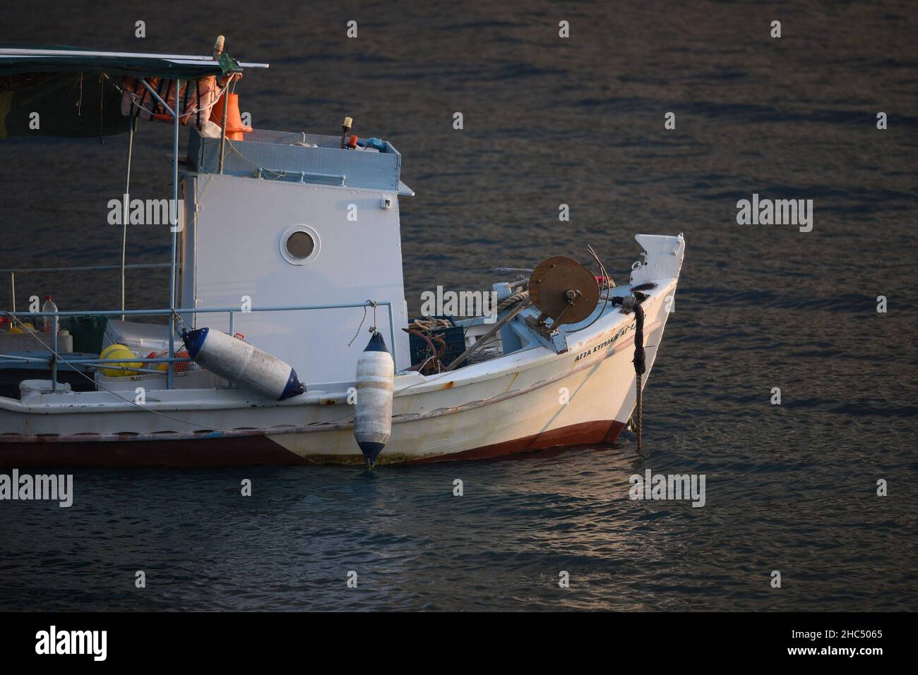 Malerische Sonnenuntergangslandschaft mit einem traditionellen griechischen Fischerboot aus Holz auf den Gewässern von Karavostasi in Lakonia, Peloponnes, Griechenland. Stockfoto