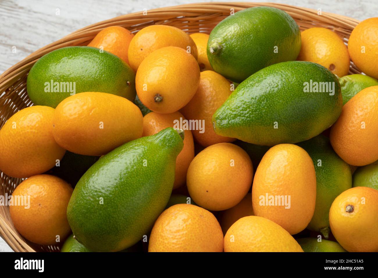 Korb mit frischen grünen ganzen limequats und orange Kumquats aus der Nähe Stockfoto