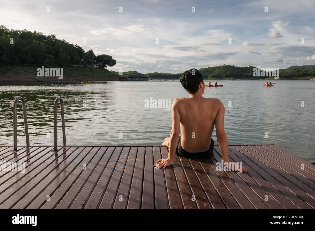 Junger asiatischer Mann, der am Abend am See relaxt Stockfoto