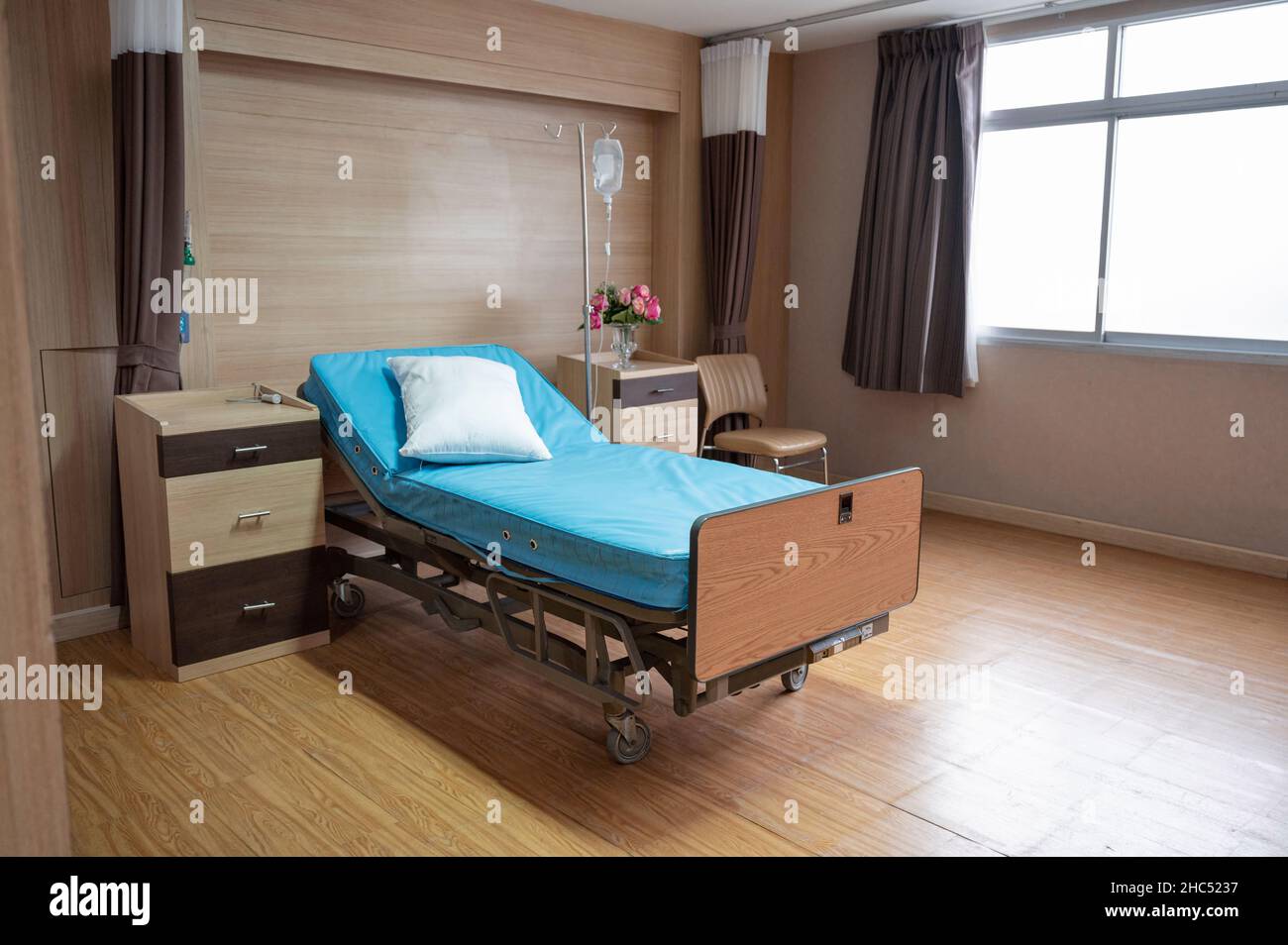 Leeres, verstellbares Patientenbett mit Kochsalzlösung im Privatzimmer auf der Krankenhausstation Stockfoto