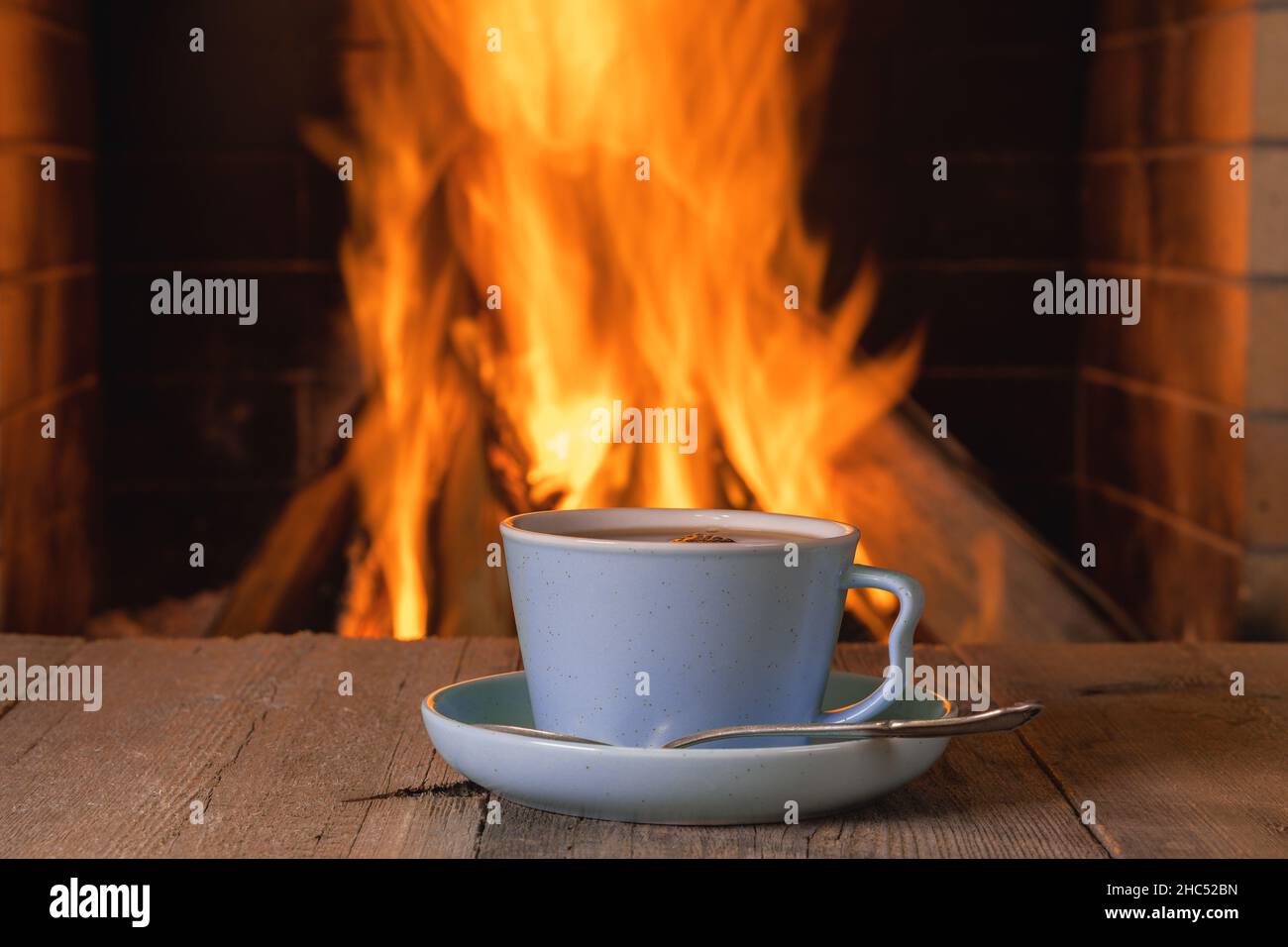 Tasse Kaffee in der Nähe von gemütlichen Kamin Hintergrund Stockfoto
