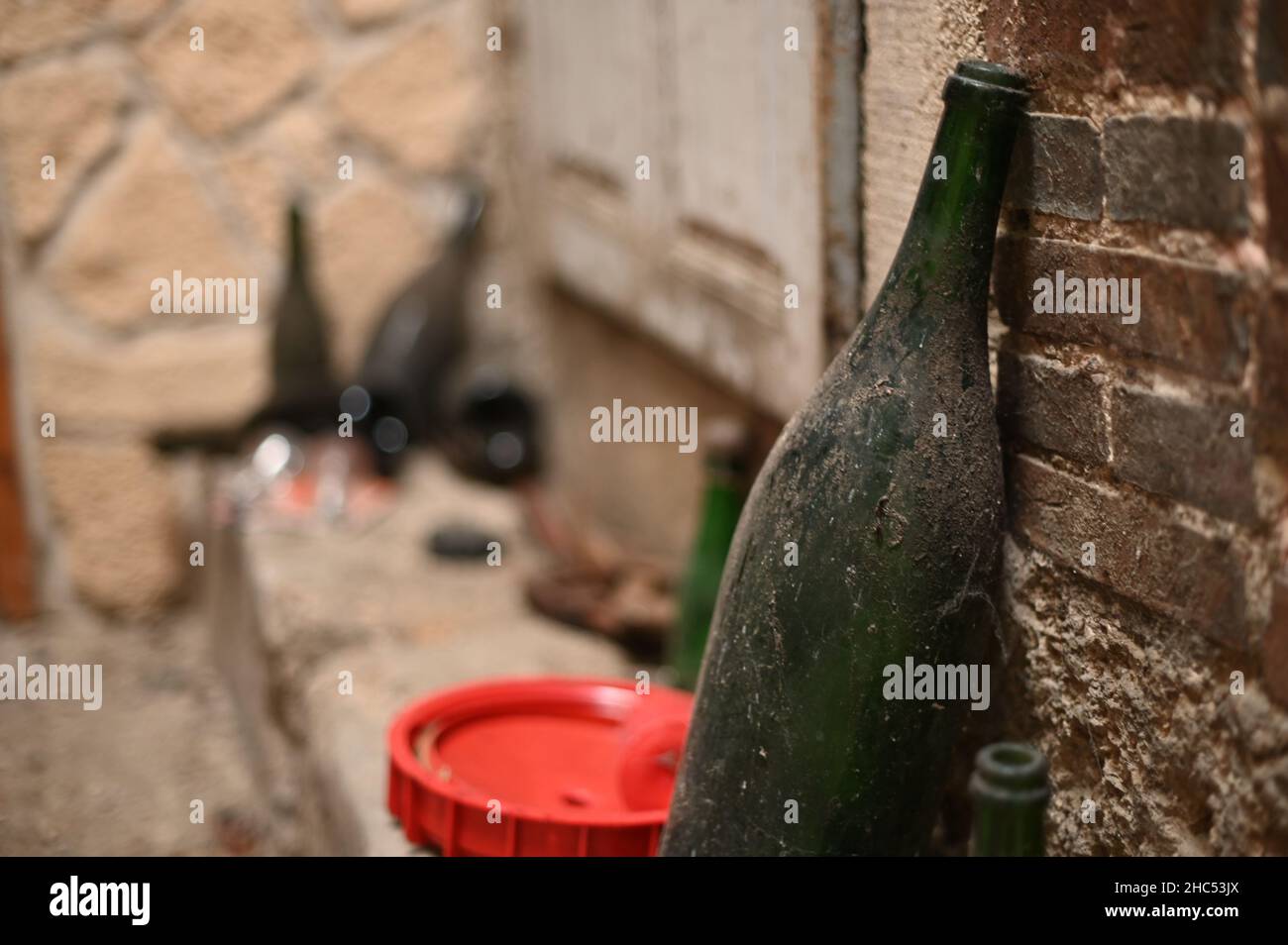 Nahaufnahme einer alten, schmutzigen Flasche, die an einer Wand gelehnt ist Stockfoto