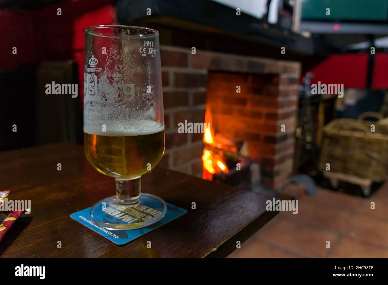 Halb betrunkenes Bier mit einem defokussierten Kamin im Hintergrund. Stockfoto