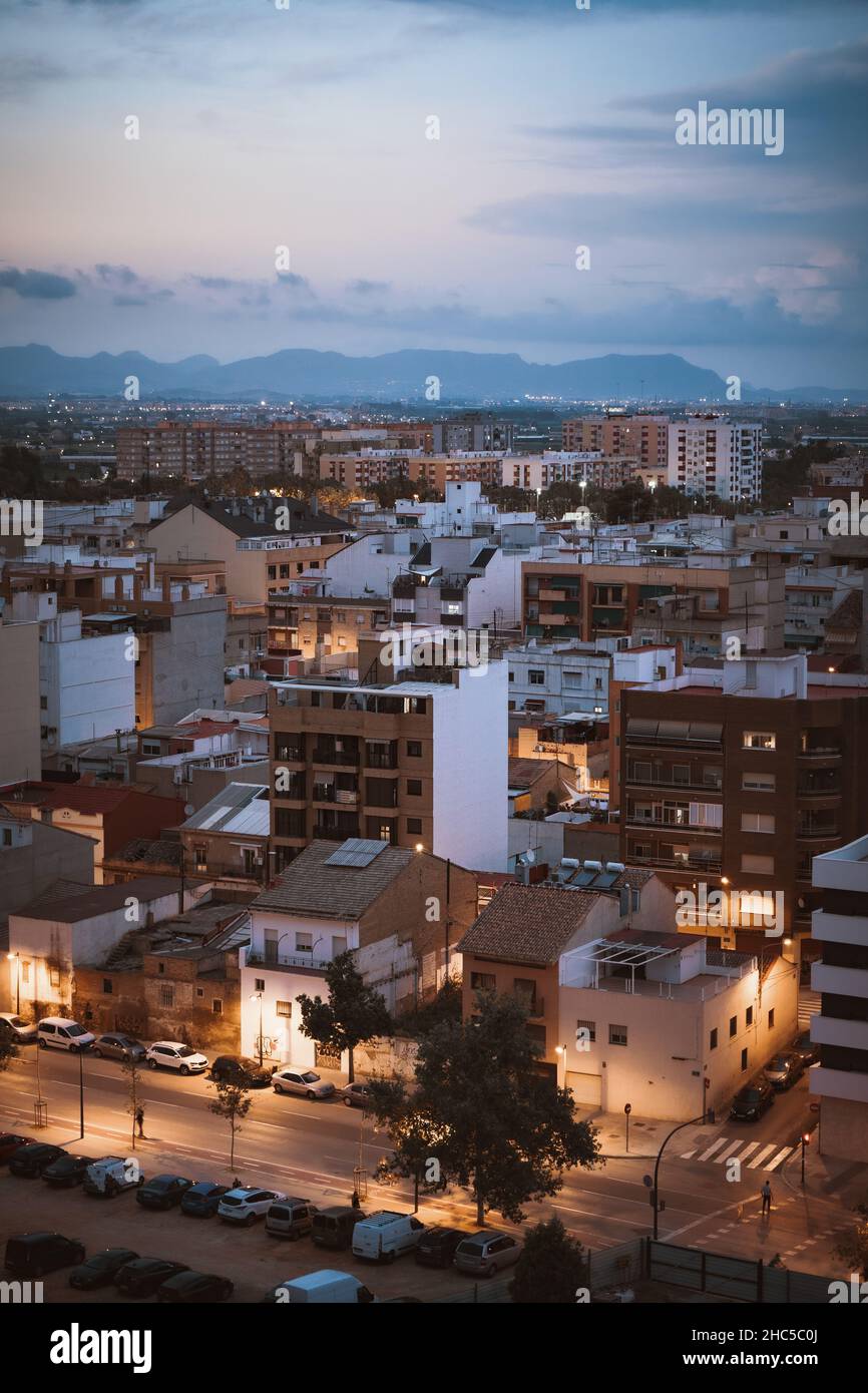 Vertikale Luftaufnahme von dichten Gebäuden auf dem Hintergrund von Bergen unter einem blauen Himmel in Valencia Stockfoto