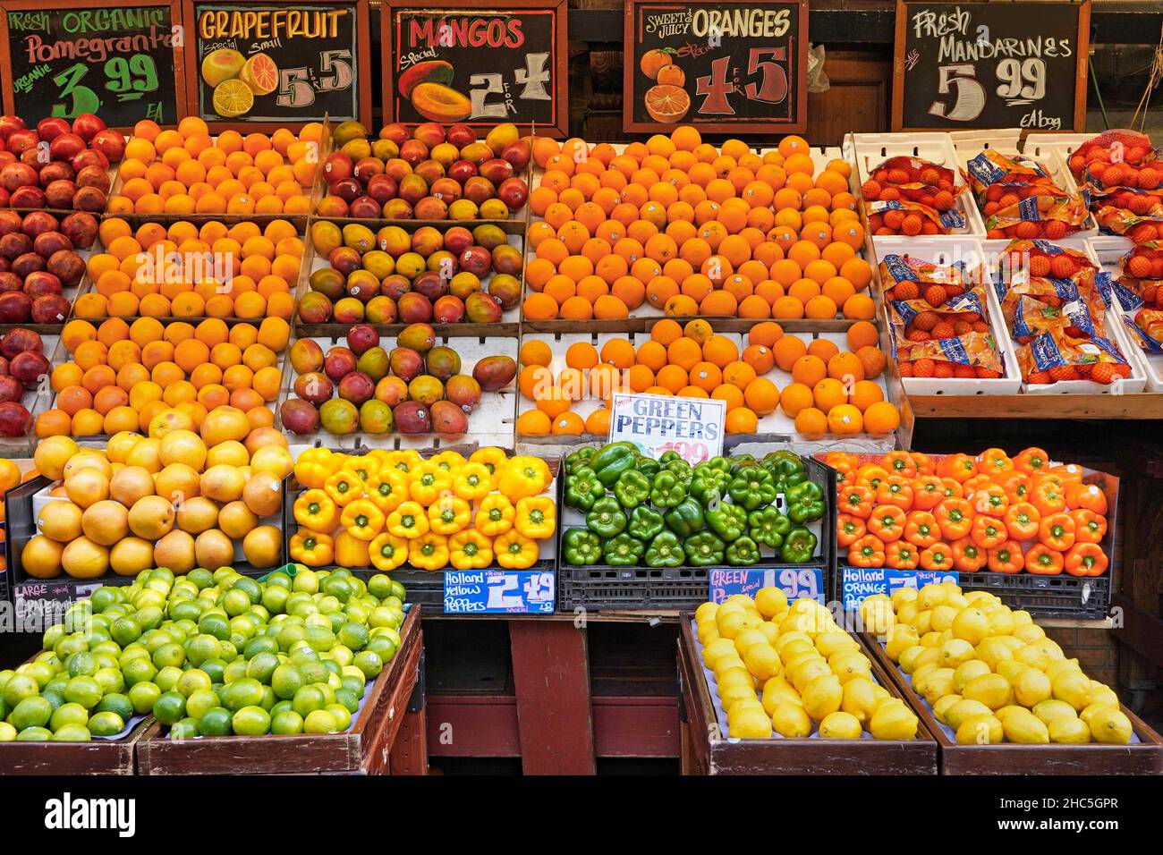Obst- und Gemüseverkäufer im Freien auf dem Tisch auf dem Bürgersteig vor einem Lebensmittelgeschäft Stockfoto