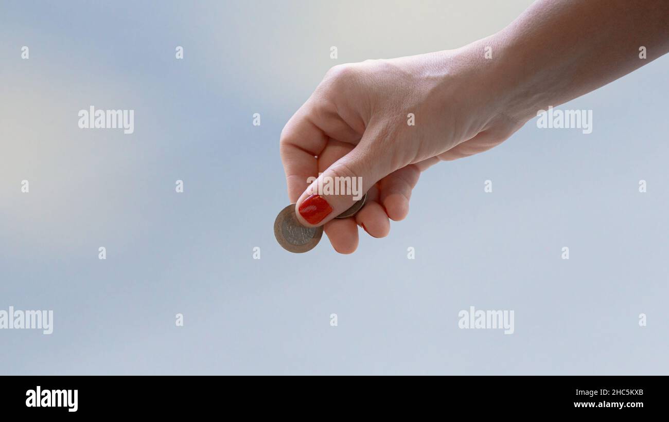 Frau Hand hält Münze vor isoliertem Hintergrund Stockfoto