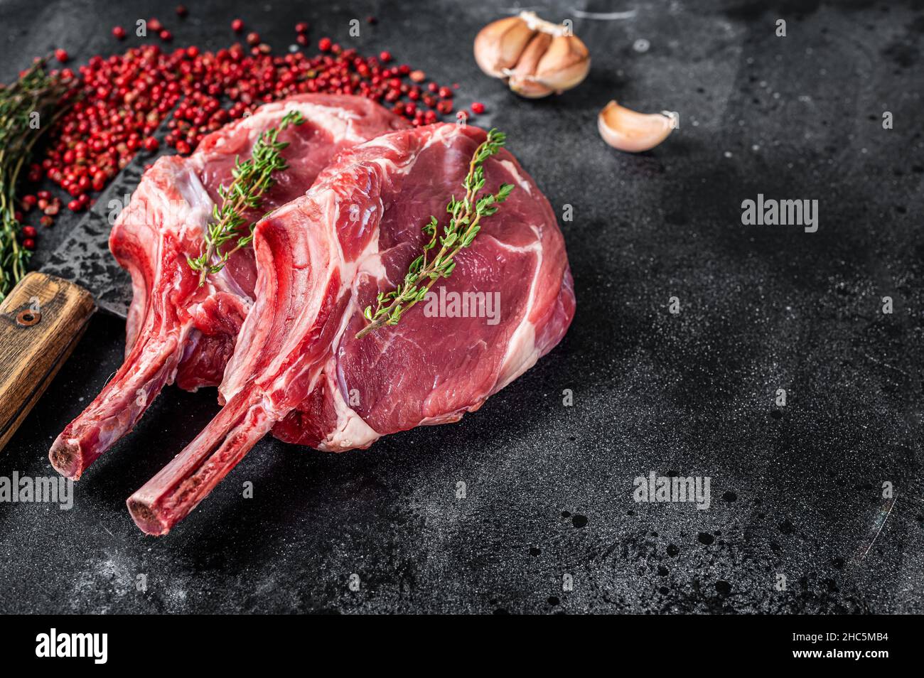 Rohe Tomahawk Rib Kalbssteaks auf Fleischspalter. Schwarzer Hintergrund. Draufsicht. Speicherplatz kopieren Stockfoto